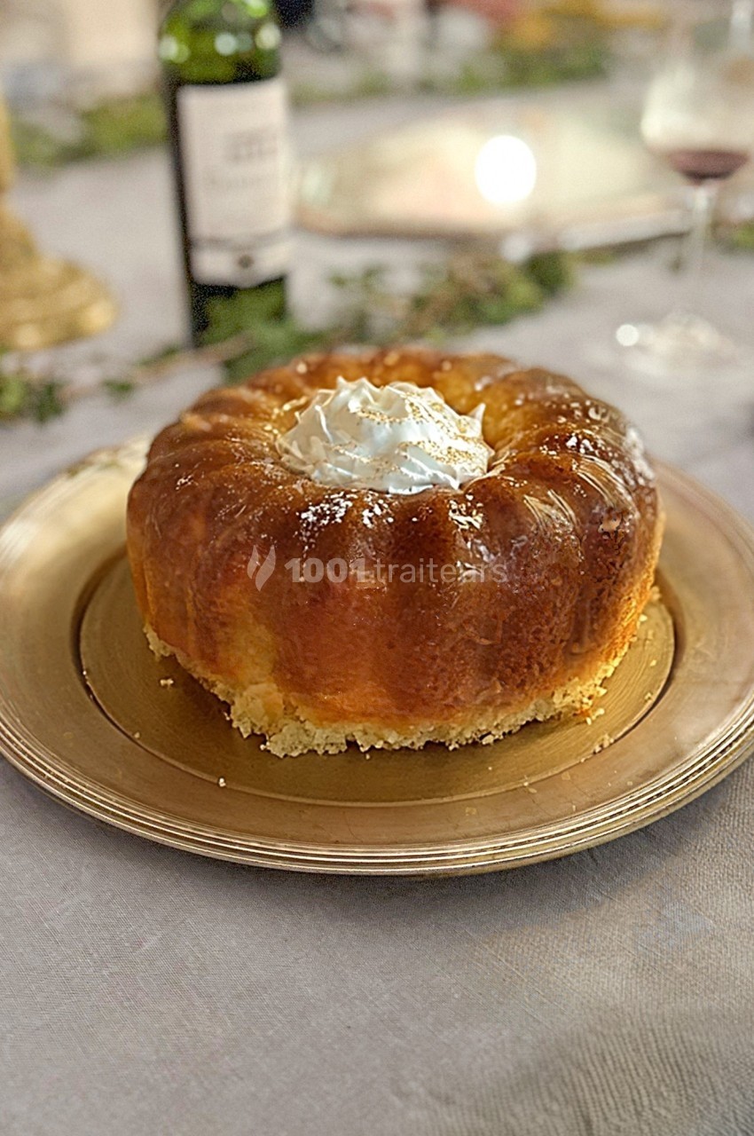 Gâteau baba au rhum avec chantilly, présenté sur une assiette dorée sur une table décorée.