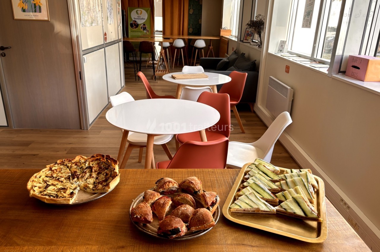 Des tables avec des chaises colorées dans un café lumineux, avec des plats de viennoiseries et tartes sur une table au…