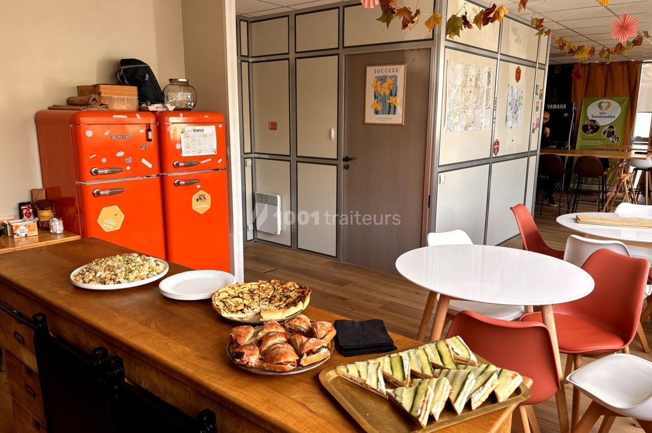 Buffet avec quiches, croissants et sandwichs dans une salle conviviale décorée avec des tons automnaux.
