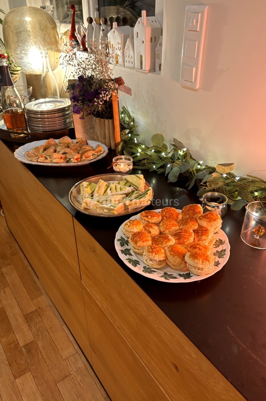 Plateau de bouchées apéritives variées disposé sur un buffet décoré de guirlandes lumineuses et de plantes.