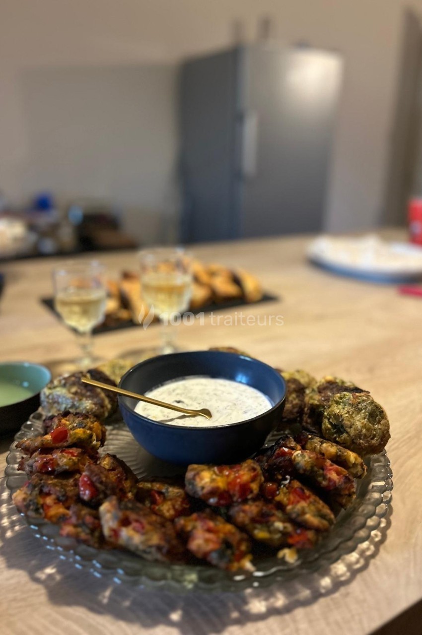 Assiette de boulettes de légumes servies avec une sauce blanche, posée sur une table en bois dans une cuisine.