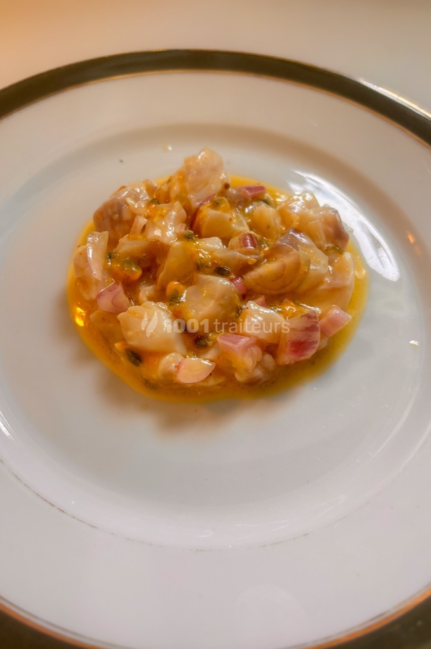Assiette contenant un tartare de poisson frais, présenté avec une sauce légèrement colorée.