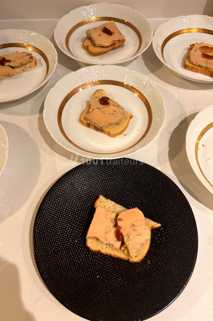 Tranches de foie gras sur pain toasté, garnies de confiture, présentées sur des assiettes blanches et une noire.