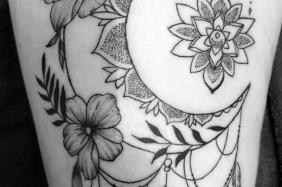 Tatouage floral noir et gris sur une cuisse, représentant des fleurs et des feuilles avec des détails délicats.