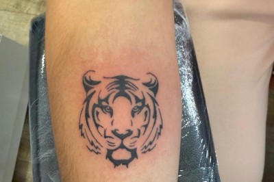 Tatouage floral noir et gris sur une cuisse, représentant des fleurs et des feuilles avec des détails délicats.