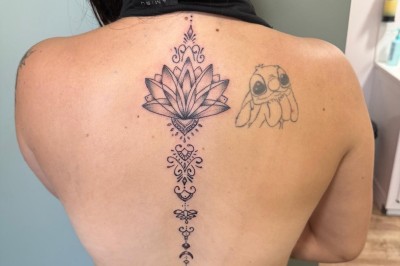 Tatouage floral noir et gris sur une cuisse, représentant des fleurs et des feuilles avec des détails délicats.