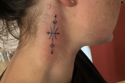 Tatouage floral noir et gris sur une cuisse, représentant des fleurs et des feuilles avec des détails délicats.