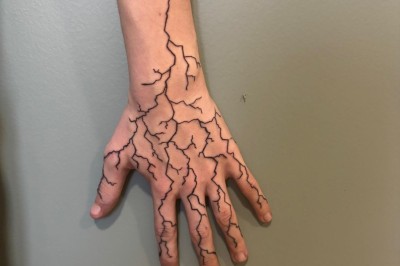 Tatouage floral noir et gris sur une cuisse, représentant des fleurs et des feuilles avec des détails délicats.