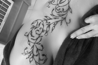 Tatouage sur une jambe représentant un papillon dont une aile se transforme en un bouquet de fleurs détaillées.