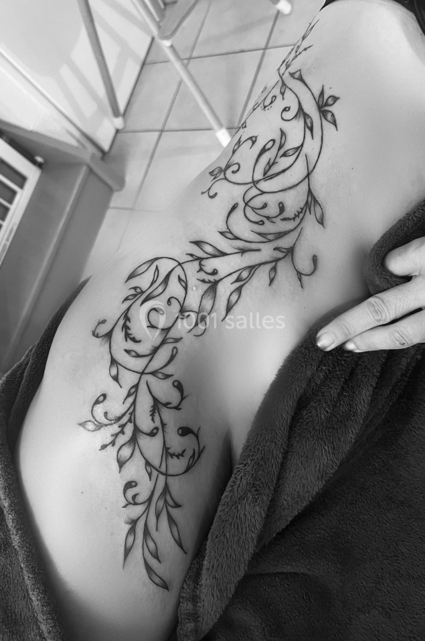 Tatouage floral détaillé couvrant le flanc d'une personne, photographié en noir et blanc.