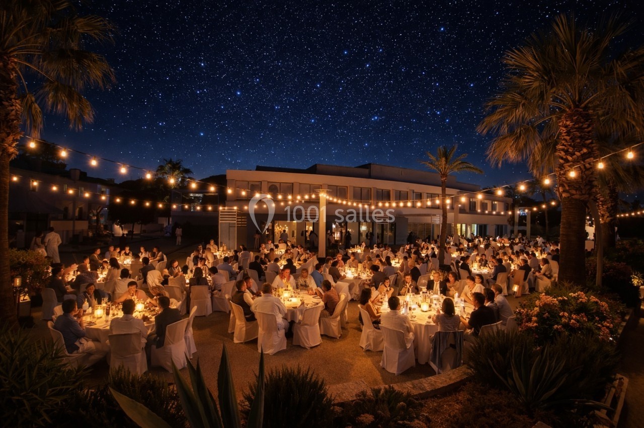 Dîner en plein air sous un ciel étoilé, avec des invités assis à des tables illuminées par des guirlandes lumineuses.