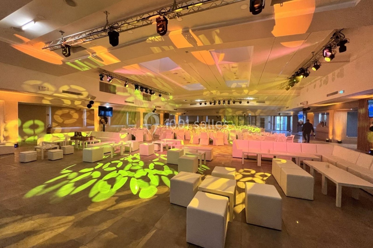 Salle de réception moderne avec éclairage coloré, sièges blancs et décorations lumineuses au sol.