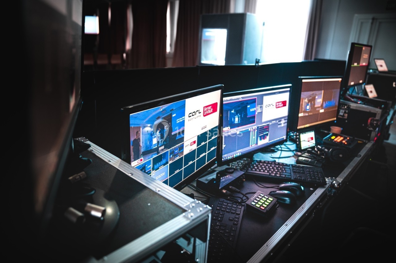 Poste de contrôle audiovisuel avec plusieurs écrans affichant des interfaces de production et des équipements techniques.