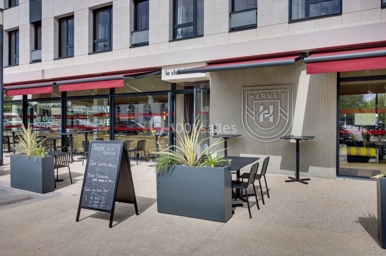 Façade d'un restaurant avec terrasse, tables, chaises, plantes en bac et ardoise affichant le menu du jour.