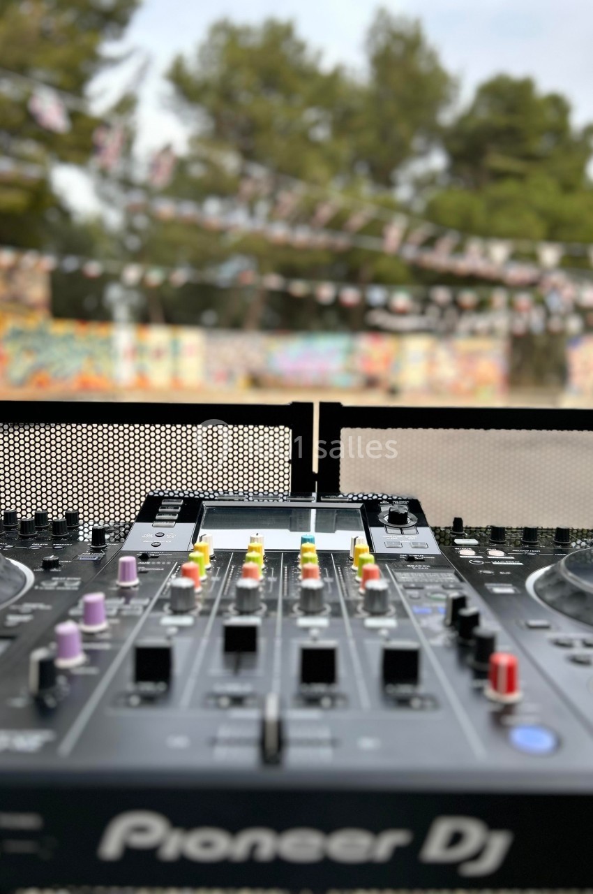 Table de mixage DJ en gros plan, avec un arrière-plan flou de décorations suspendues et de graffitis colorés.