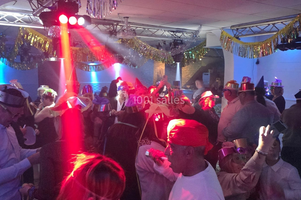 Personnes dansant et célébrant sous des lumières colorées dans une salle décorée avec des guirlandes festives.