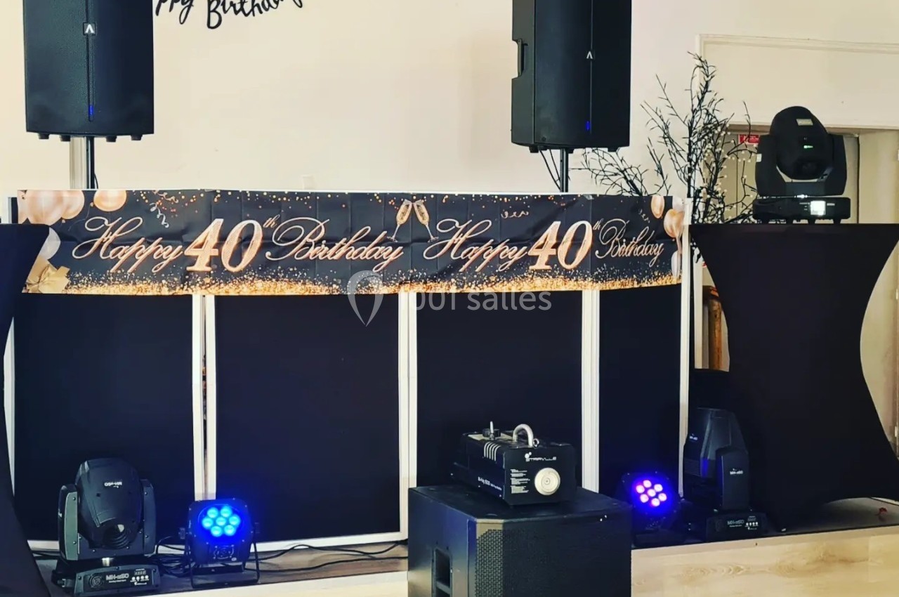 Décoration d'anniversaire avec une bannière ’Happy 40 Birthday’, des enceintes et des éclairages sur une scène.