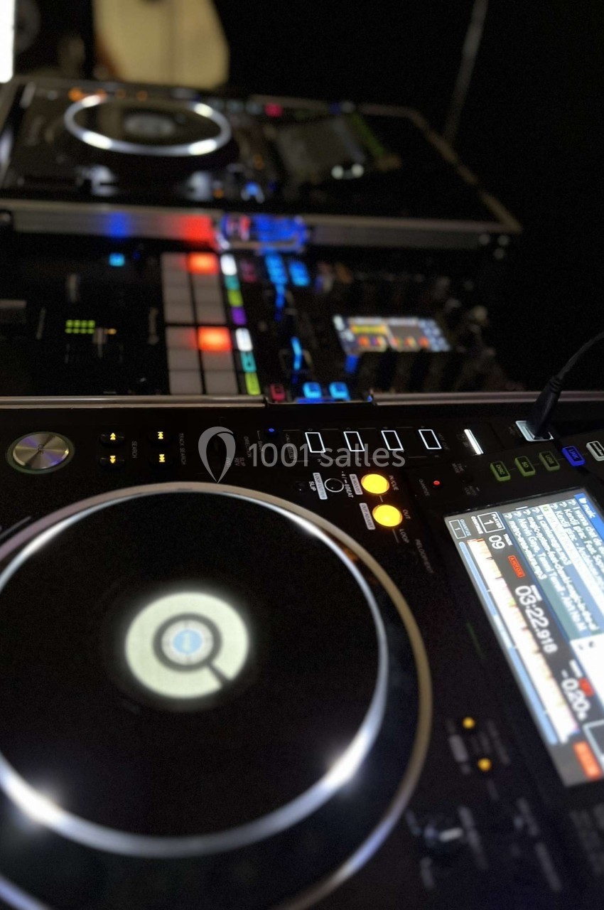 Deux platines DJ et une table de mixage éclairées, avec des boutons et écrans lumineux en gros plan.