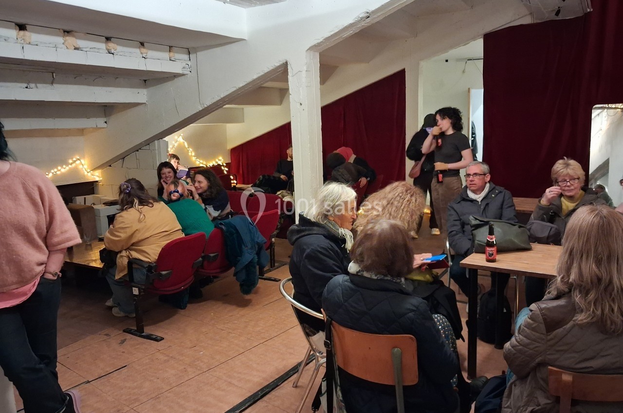 Personnes assises dans une salle conviviale avec des tables, des chaises et des lumières décoratives.