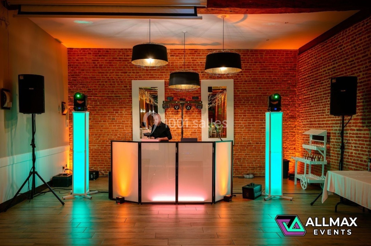Configuration d'une piste de danse avec un DJ, éclairages colorés, enceintes et décor en briques apparentes.