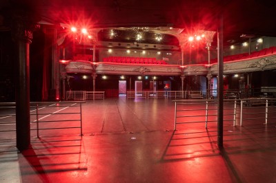 Intérieur d'une salle de spectacle avec balustrade, colonnes décoratives et éclairage tamisé.