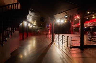 Intérieur d'une salle de spectacle avec balustrade, colonnes décoratives et éclairage tamisé.