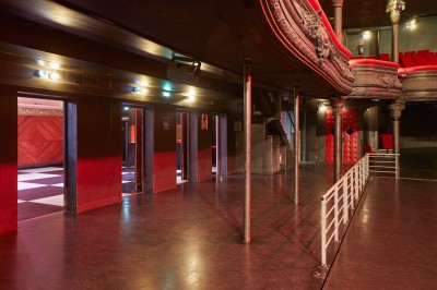 Intérieur d'une salle de spectacle avec balustrade, colonnes décoratives et éclairage tamisé.