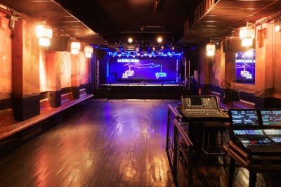 Hall d'entrée avec murs aux formes ondulées, sol à motifs géométriques et escalier menant à une porte noire.