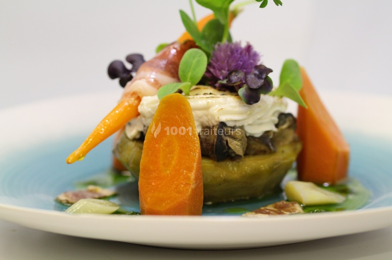 Plat gastronomique composé de légumes colorés, fromage frais et herbes, présenté sur une assiette blanche.