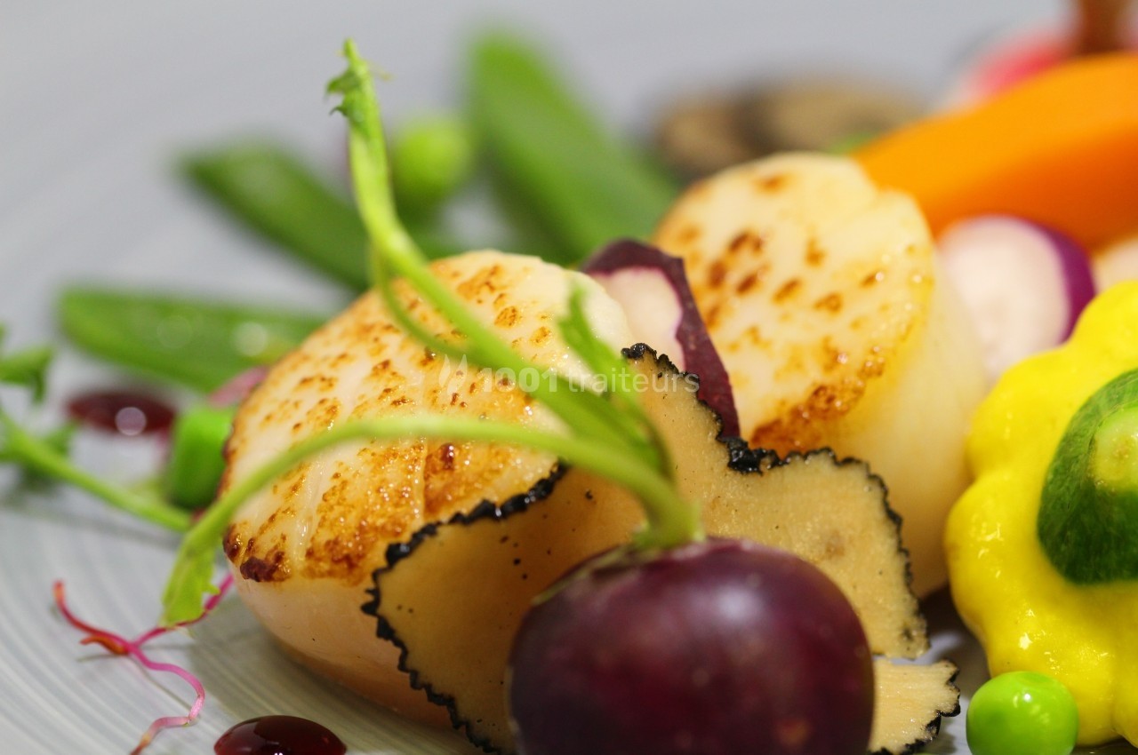 Noix de Saint-Jacques poêlées accompagnées de légumes colorés, tranches de truffe et sauce décorative.
