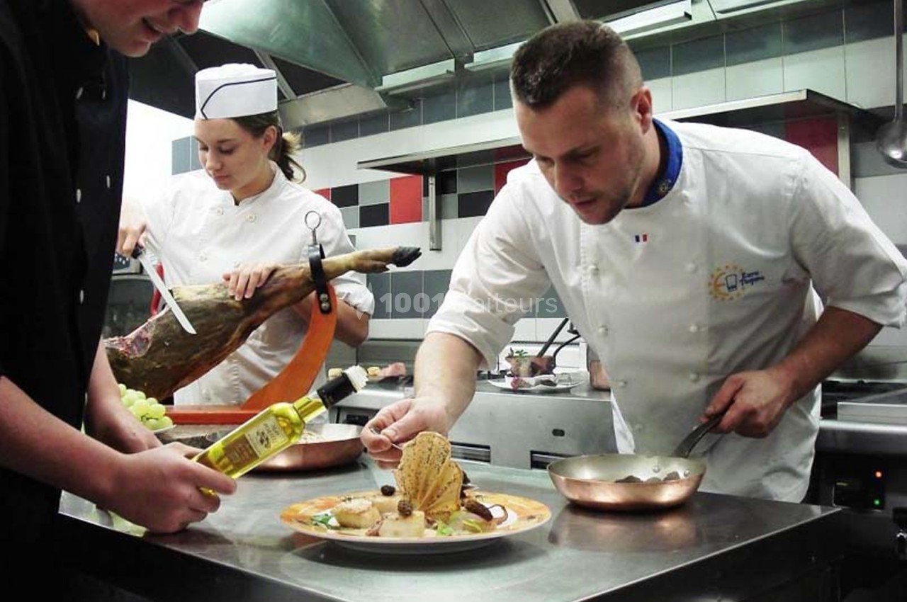Un chef et son équipe préparent un plat gastronomique dans une cuisine professionnelle.