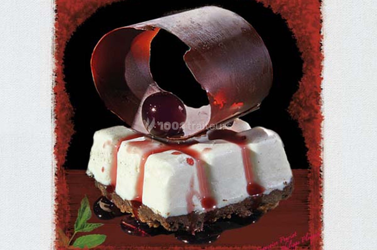 Dessert composé d'une base biscuitée, mousse blanche, coulis de cerises et décoration en chocolat.