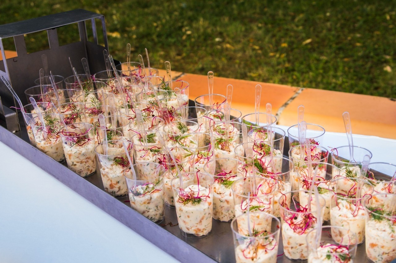 Verrines individuelles de salade garnies d'herbes fraîches et de radis, disposées sur un plateau en extérieur.
