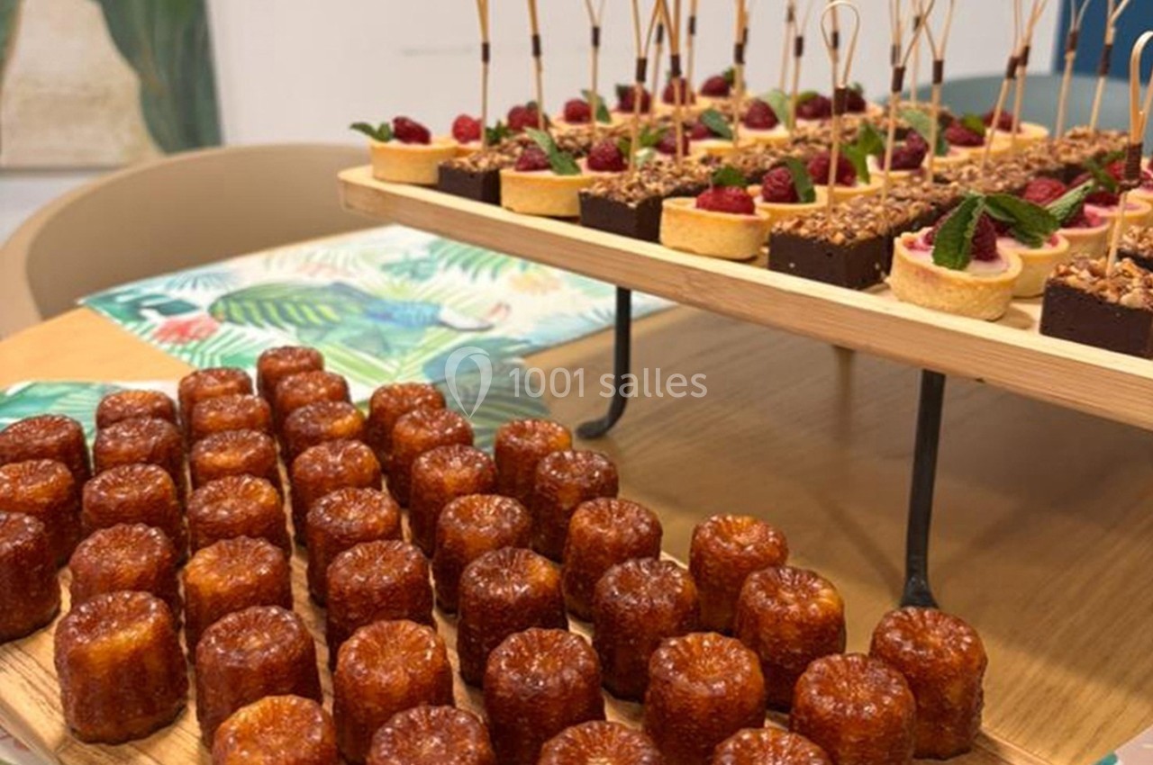 Plateau de cannelés et assortiment de desserts variés présentés sur une table en bois.