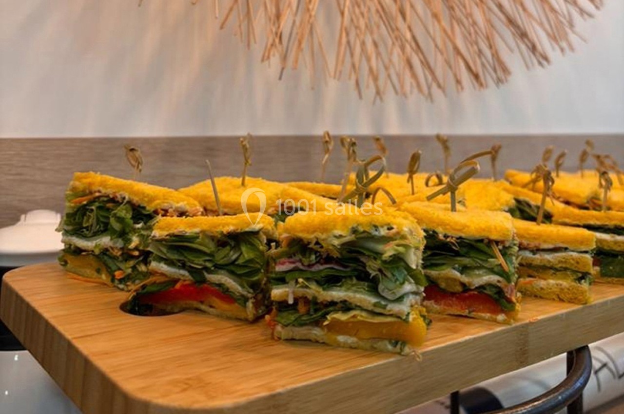 Assortiment de sandwichs végétariens colorés sur un plateau en bois, garnis de légumes et maintenus par des piques.