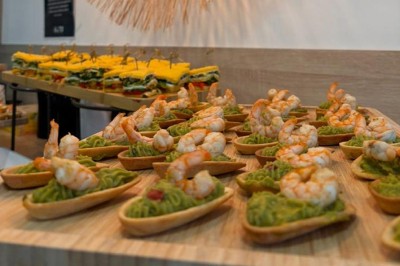 Table ronde dressée pour un repas, avec nappes blanches, couverts, verres, pains et centre de table floral.