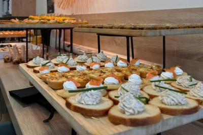 Table ronde dressée pour un repas, avec nappes blanches, couverts, verres, pains et centre de table floral.