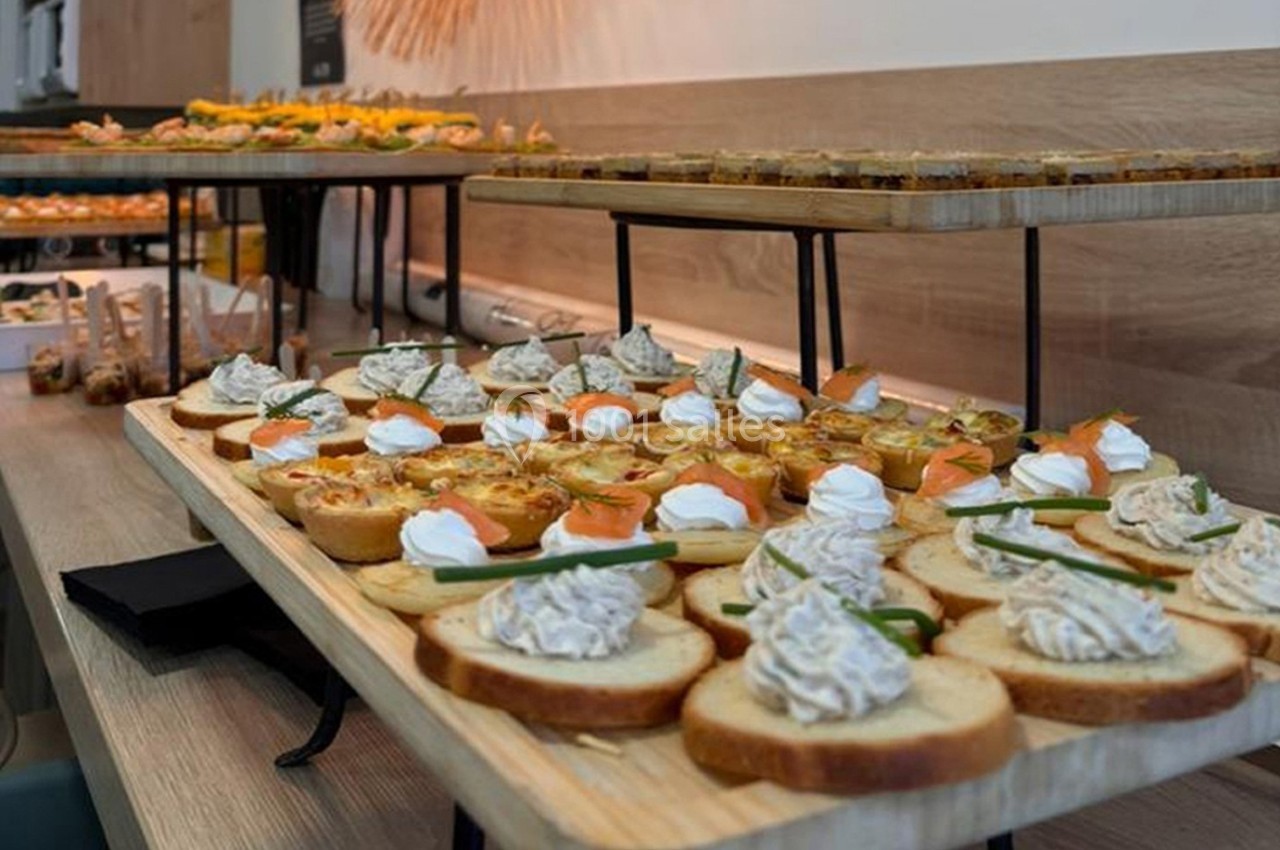 Plateau de toasts variés avec garnitures salées, disposés sur une table en bois dans un cadre de réception.