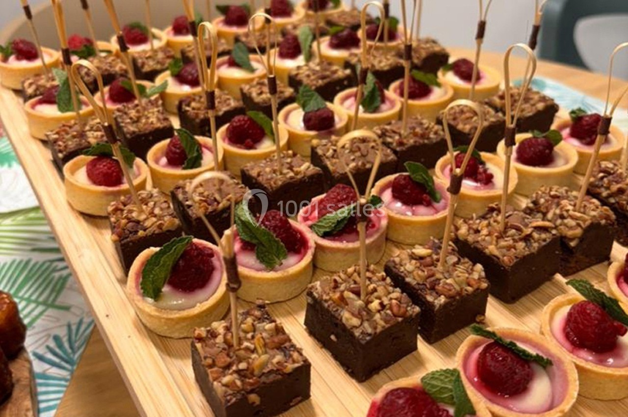 Plateau de mignardises composé de tartelettes aux framboises et de bouchées au chocolat décorées de noix et de menthe.