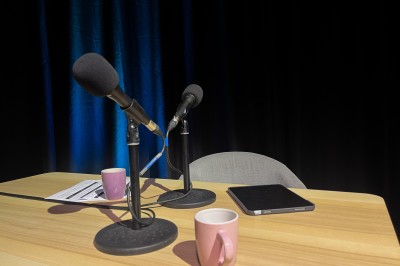 Miniature Podcast Atelier de création avec une table remplie de matériaux, une caméra suspendue et une poupée en tissu en cours de fabrication.