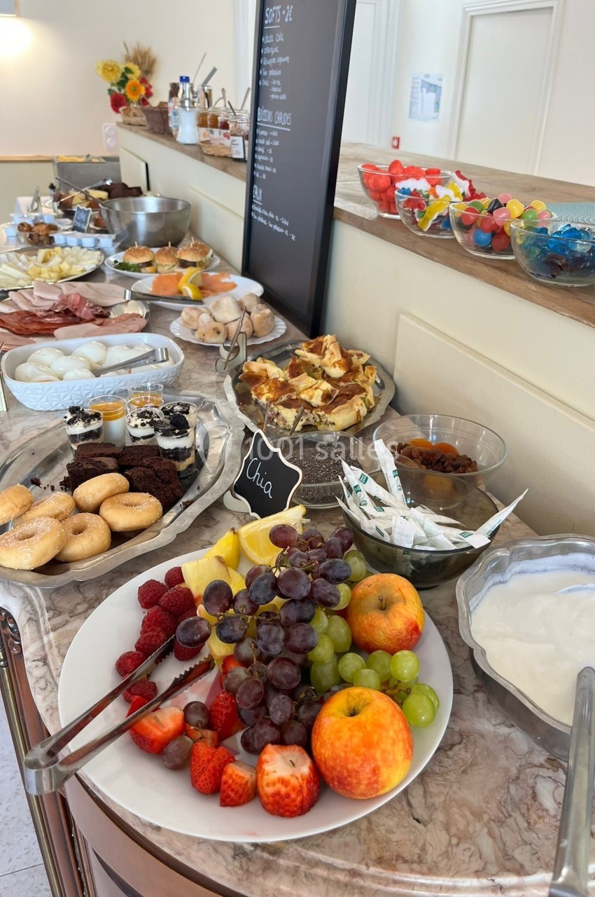 Buffet de petit-déjeuner avec fruits frais, viennoiseries, desserts, yaourt, et options salées sur une table en marbre.