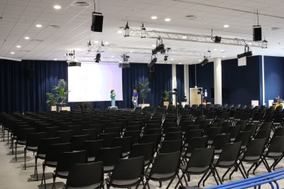 Miniature Forum 200/300 Salle de conférence moderne avec poufs colorés, tables basses et écrans affichant une présentation.