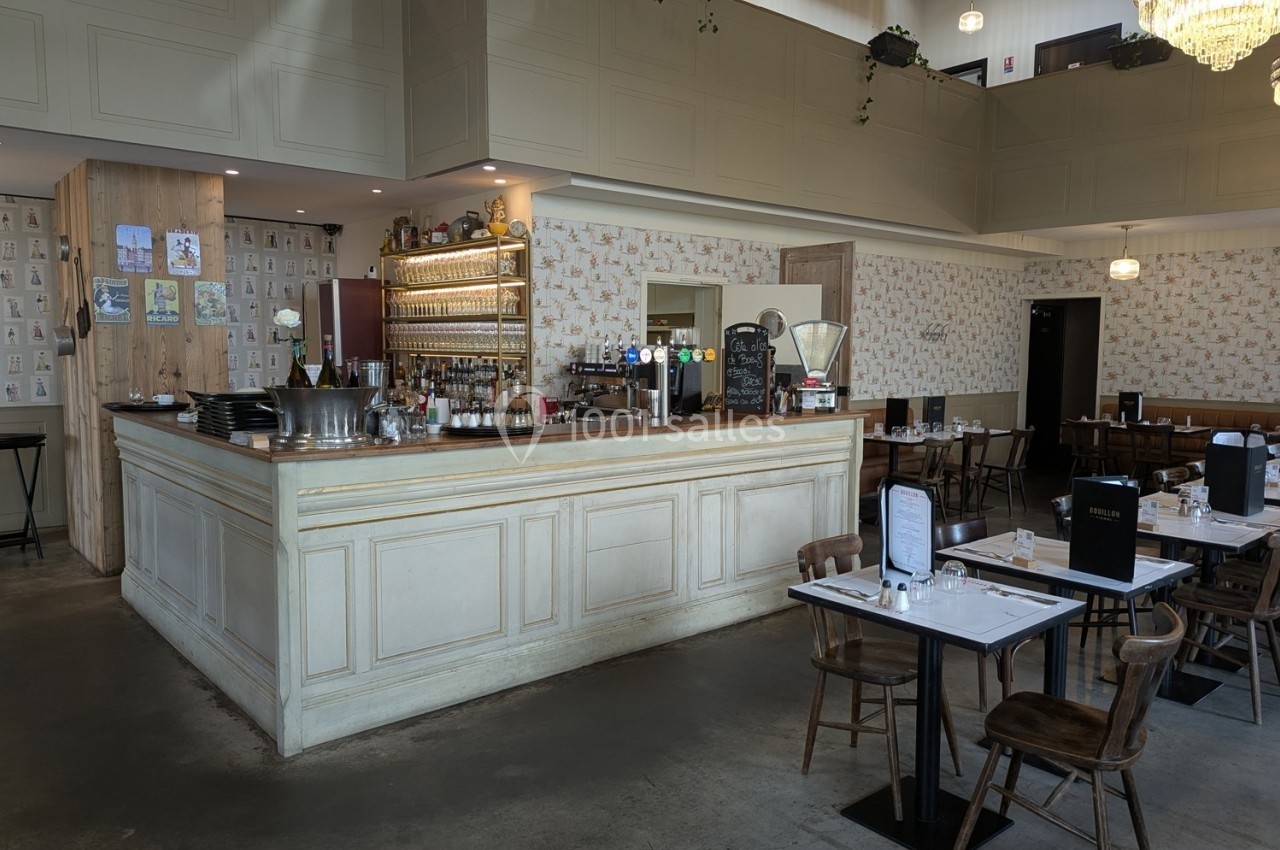 Salle de restaurant lumineuse avec un comptoir en bois clair, des tables dressées et une décoration murale vintage.