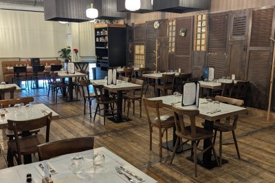 Miniature Mezzanine Poulet rôti garni d'oignons caramélisés sur une assiette, avec une main utilisant une fourchette en arrière-plan.