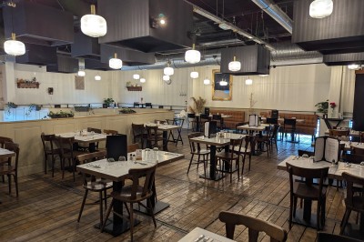 Miniature Mezzanine Poulet rôti garni d'oignons caramélisés sur une assiette, avec une main utilisant une fourchette en arrière-plan.