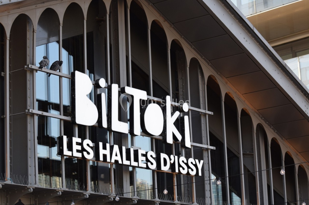 Façade d'un bâtiment avec l'enseigne ’BilToki Les Halles d'Issy’ et des arches vitrées en arrière-plan.