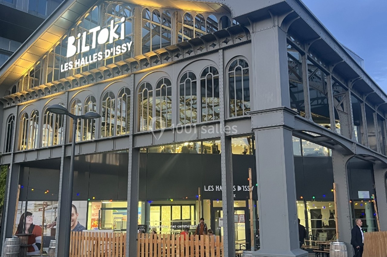 Façade des Halles d'Issy, bâtiment en verre et métal avec enseigne lumineuse ’BilToki’, en début de soirée.