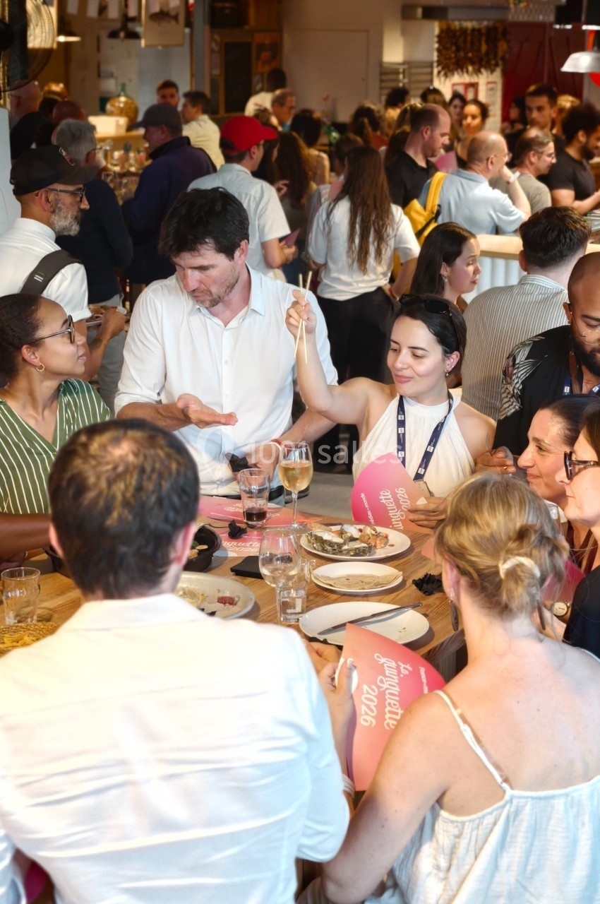 Groupe de personnes partageant un repas et discutant dans un restaurant animé.