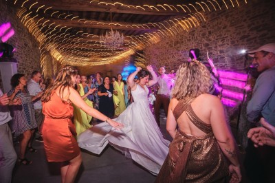Un couple danse sous des lumières colorées et une ambiance de fumée lors d'une réception festive.
