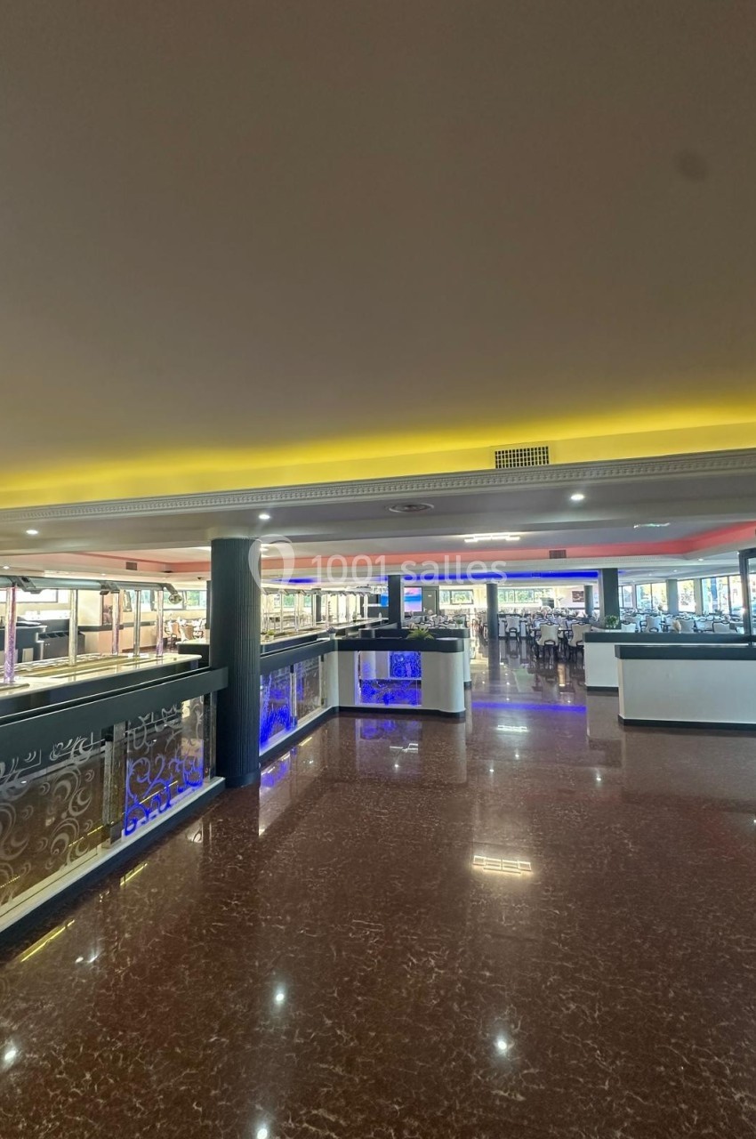 Intérieur d'un restaurant spacieux avec un sol en marbre, des buffets éclairés et des tables disposées au fond.
